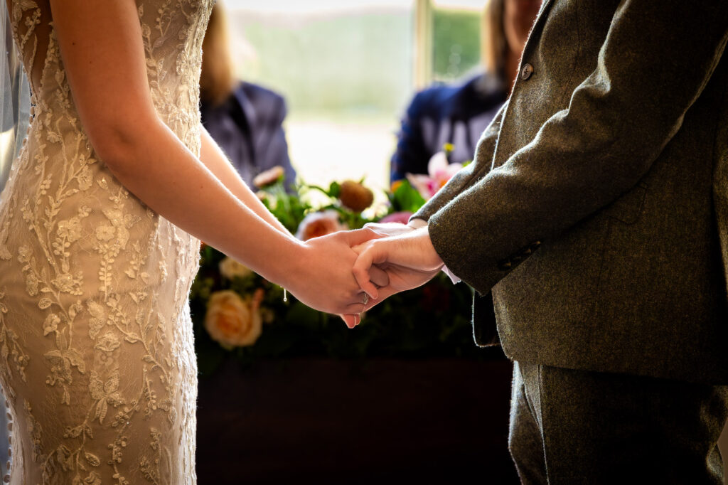 A bride and groom holding hands during their wedding ceremony.