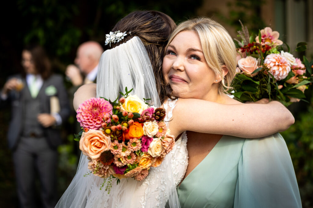 Bridesmaid in tears of happiness hugging bride.