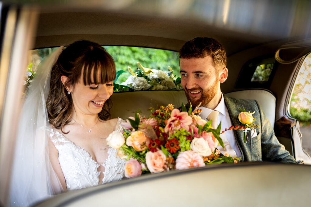 Bride and groom in the back of a Rolls Royce.