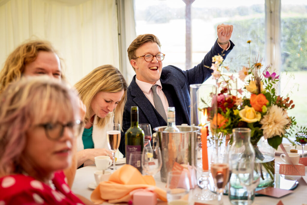 A wedding guest reacting to jokes in a speech.