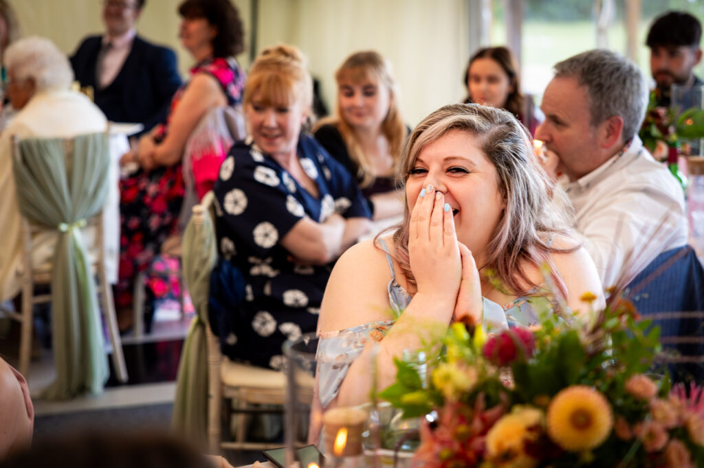 A female guest laughing at wedding speeches.