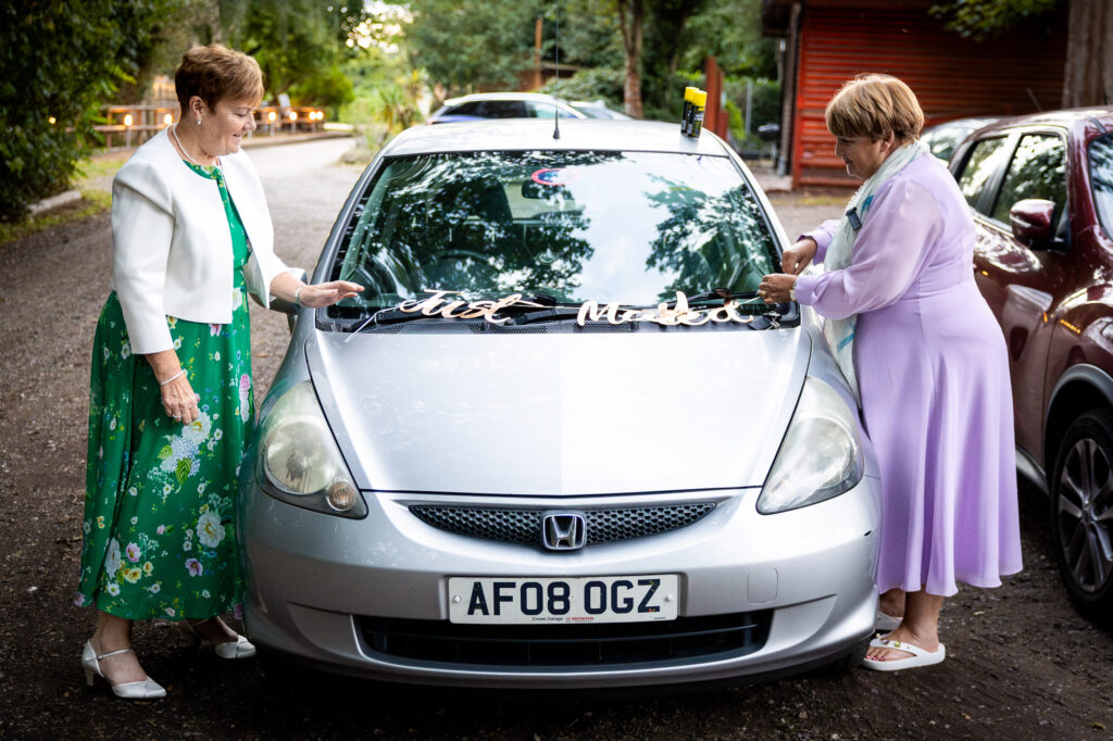 Wedding guests decorating the bride and groom's car.