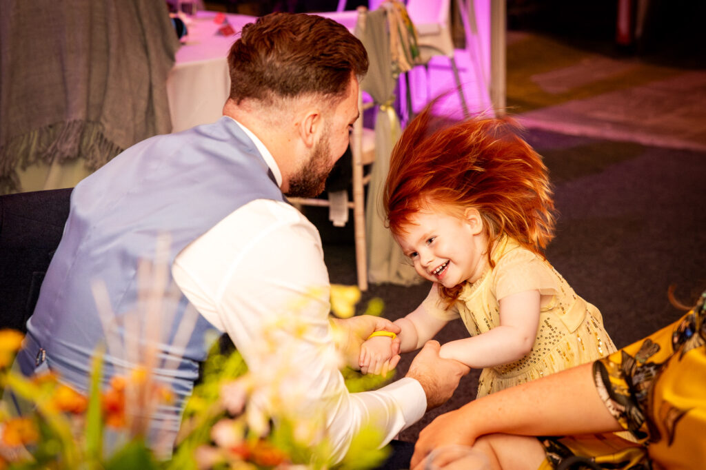 A girl and her dad having fun at a wedding reception.