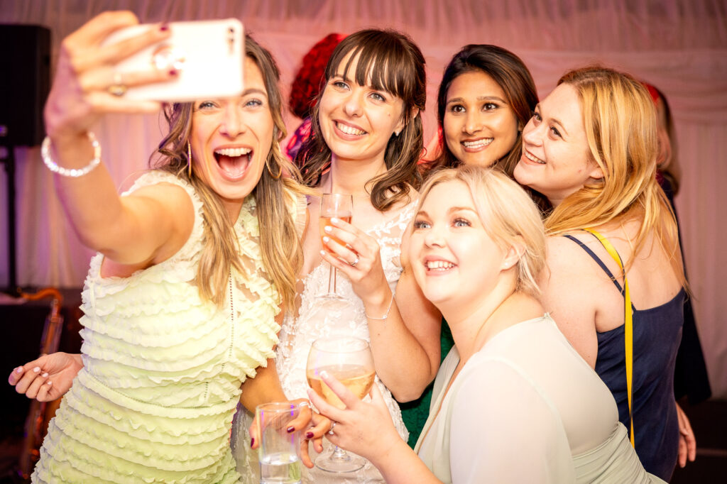 A bride and her friends taking a selfie at a wedding reception.